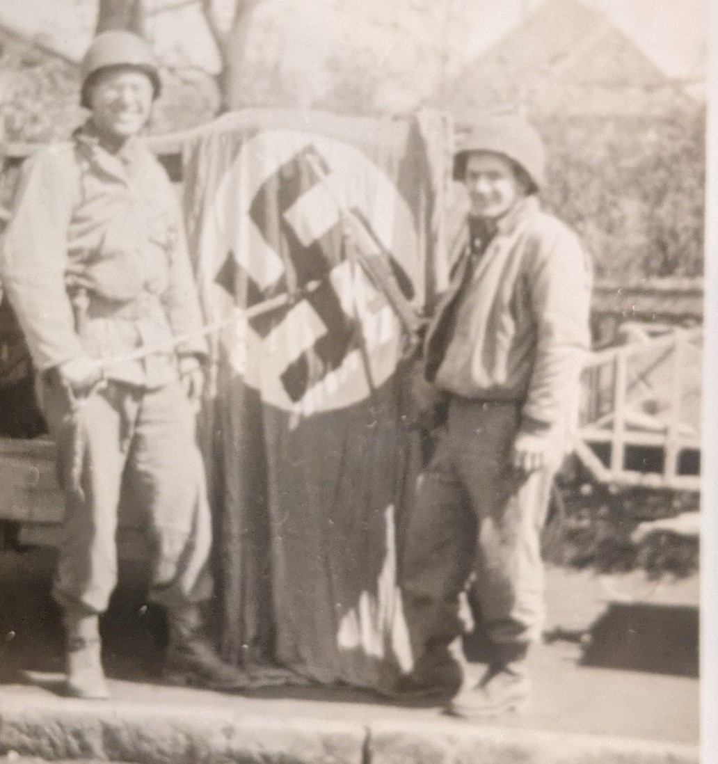 T/4 Irving Klein is shown with two nice war trophies: a captured Nazi flag, and an NCOs dress saber. The details of his story are annotated below.