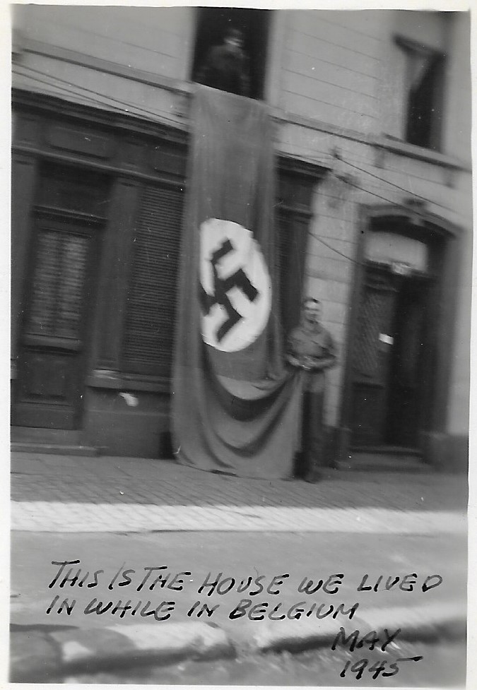 Photo depicting a captured German Party Banner draped from the upper baclony of a house in Belgium. No other annotation is available, nor are any town or street names. The uniforms of the soldiers in the blurry image do not show unit insignia.